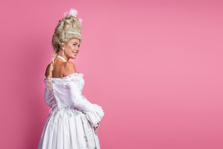 Elegant portrayal of a woman dressed in an exquisite baroque costume standing against a vibrant pink...