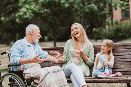 Funny park bench family moment with grandpa in a wheelchair sharing laughter love and care with...