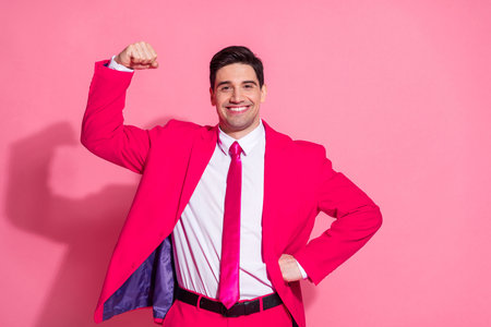 Confident young man in vibrant pink suit striking a power pose against pink background radiating charm and eleganceの写真素材