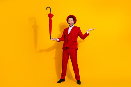 Funny man in red suit with umbrella strikes a bold pose against bright yellow backdrop for a stylish...
