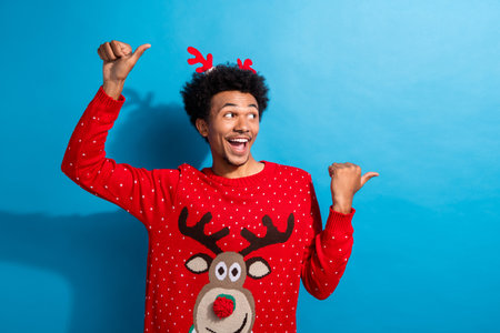 Photo portrait of pretty young male point look empty space wear red christmas sweater masquerade theme party on blue color backgroundの写真素材