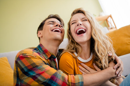 Photo of cute young couple hugging laughing cozy day light spring summer home interior living roomの写真素材