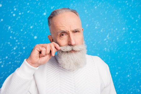 Photo of focused aged man arm touching moustache look camera wear sweater isolated on blue color backgroundの写真素材