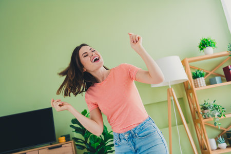 Young woman enjoying a lively day indoors, expressing joy and happiness in a comfortable living environment, while embracing a trendy styleの写真素材