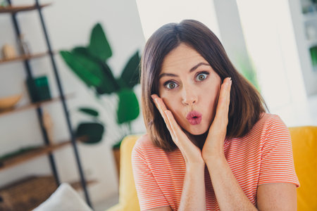 Surprised young woman in a striped t-shirt spending a cheerful day at homeの写真素材