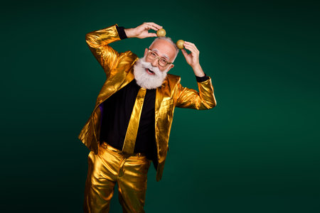 Mature man in golden suit celebrating with playful energy on green backgroundの写真素材