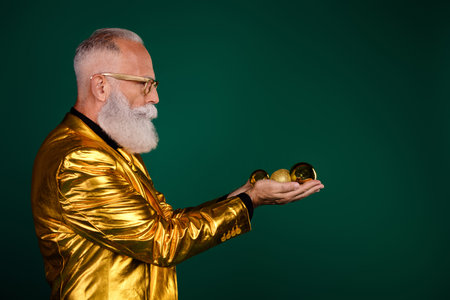 Charismatic gentleman in a golden suit holding festive ornaments against a green backdrop, embodying vintage charm and elegance.の写真素材