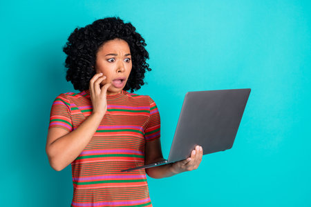 Portrait of young woman with laptop isolated on turquoise color backgroundの写真素材