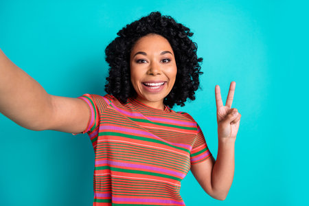 Photo of young girl selfie v-sign wear t-shirt isolated on teal color backgroundの写真素材