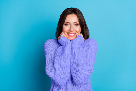 Portrait of attractive cheerful pleased delighted girl enjoying wearing cosy jumper isolated over vivid blue color backgroundの写真素材