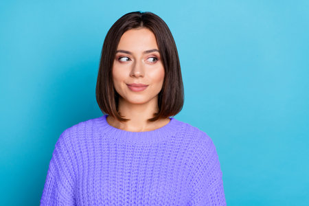 Portrait of attractive girlish cheerful girl looking aside overthinking isolated over bright blue color backgroundの写真素材