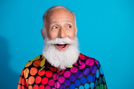 Photo of eccentric funky aged man look empty space ad wear shirt isolated on blue color background