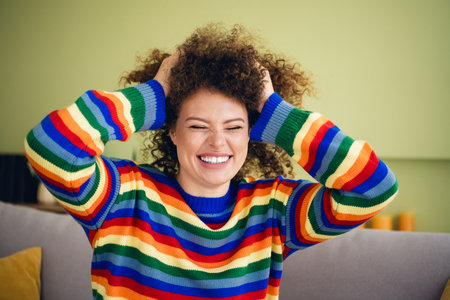 Portrait of pretty young woman sit sofa touch hair wear sweater modern interior flat indoorsの写真素材