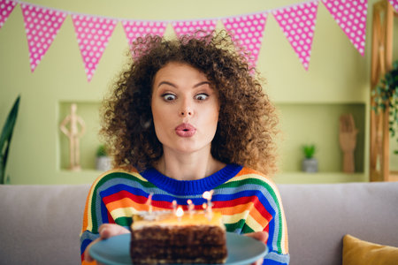 Portrait of pretty young woman blow air cake candle fire celebrate birthday modern interior flat...