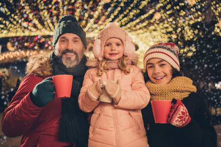 Photo of cute pretty young husband school girl boy drinking xmas beverages outdoors city fairの写真素材