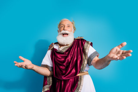 Photo of handsome senior male laughing have fun wear ancient greek god king dress isolated on blue color backgroundの写真素材