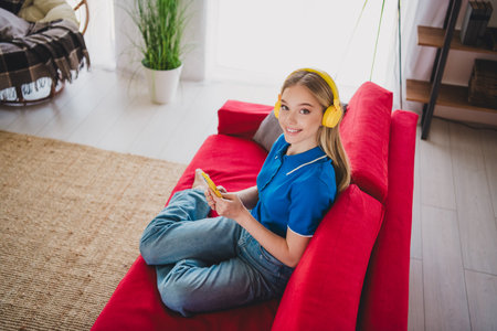 Photo of adorable cute girl wear stylish blue clothes sit divan hold phone time at home weekend indoors flat apartmentの写真素材