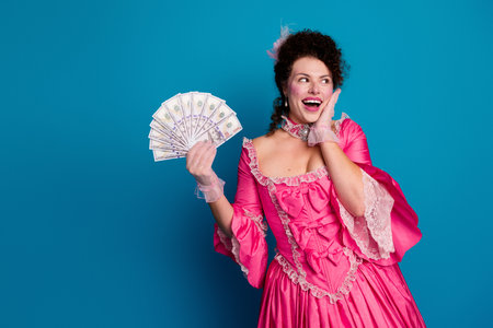 Elegant woman in a pink corset with joyful expression against a blue backgroundの写真素材