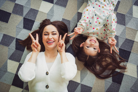 Joyful mother and daughter having fun together at home, enjoying leisure time indoors with natural light, sharing happy and funny moments.の写真素材