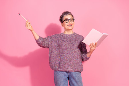 Photo of cheerful pretty lady dressed pullover writing story rising pencil empty space isolated pink...