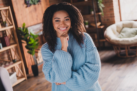 Charming young woman smiling in a stylish knitted sweater, enjoying her weekend at homeの写真素材