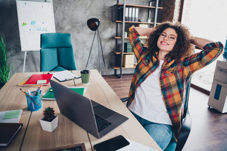 Young professional woman relaxing in casual style at modern office setting with checkered shirtの写真素材