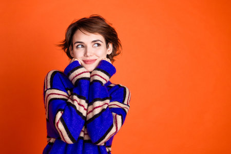 Photo of pretty lovely sweet woman wear stylish clothes arms touch face look empty space isolated on orange color backgroundの写真素材