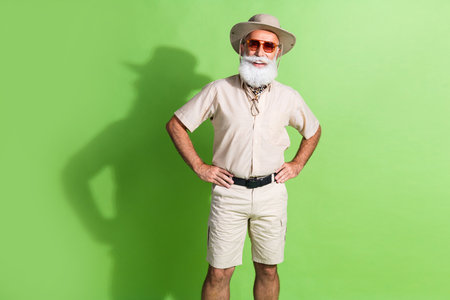 Elderly bearded traveler in fashionable safari outfit explores exotic destinations against vivid...