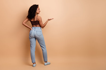 Woman in casual style posing confidently against a beige backdrop, showcasing fashionable and trendy clothing for lifestyle conceptsの写真素材