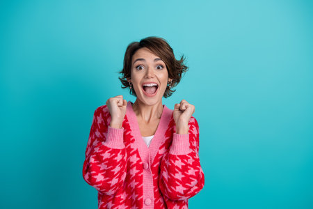 Photo portrait of pretty young girl raise fists winning wear trendy red outfit isolated on aquamarine color backgroundの写真素材