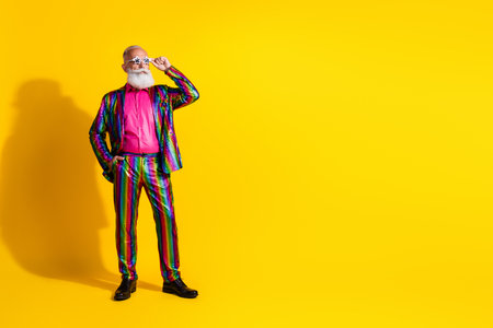 Photo of funny eccentric senior showman wear stylish striped shiny suit bachelor theme party isolated on yellow color backgroundの写真素材