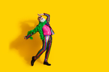 Photo of charismatic man showman wear stylish striped outfit dance night club theme party isolated on yellow color backgroundの写真素材