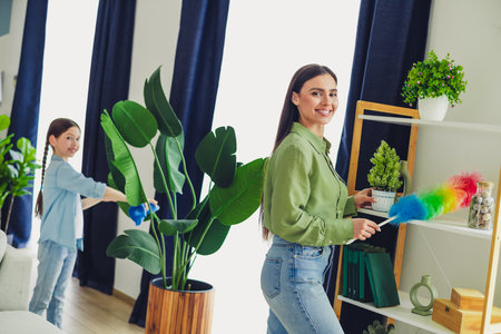 Mother and daughter bonding while cleaning their home, enjoying quality time together in a relaxed and happy atmosphereの写真素材