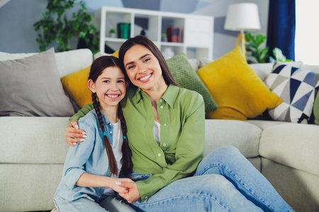 Smiling mother and daughter bonding in a cozy home setting, showcasing family love and happiness in a stylish apartmentの写真素材