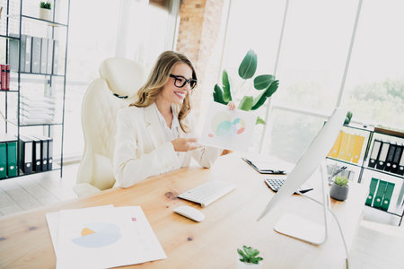 Young businesswoman presenting financial charts during an online meeting in a modern office environmentの写真素材