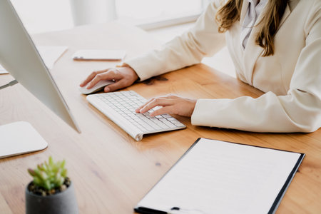 Professional businesswoman working confidently at a sleek office desk with a computer in a stylish and modern interiorの写真素材