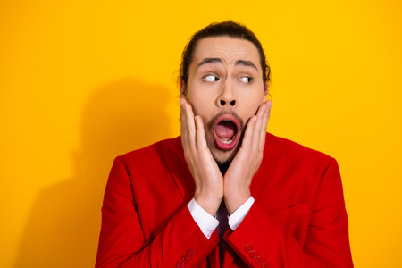 Man in red suit with surprised expression on bright yellow background makes a playful bold statement for fashion and entertainmentの写真素材