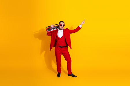 Funny red suit man with a boombox dances on a bright yellow background for a bold retro style stock photoの写真素材