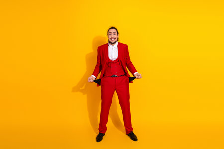 Funny bold red suited man poses playfully in bright yellow studio background for fashion advertisementの写真素材
