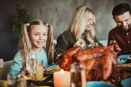 Funny family thanksgiving feast as kids and parents smile around a big roasted turkey at the table with warm autumn vibes and joyful togethernessの写真素材