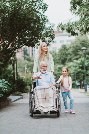 Heartwarming family moment as grandpa in wheelchair enjoys a park stroll with daughter and...