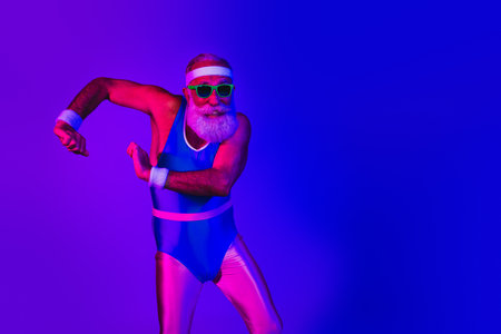 Elderly bearded man in retro blue jumpsuit dances in a vibrant purple and blue neon studioの写真素材