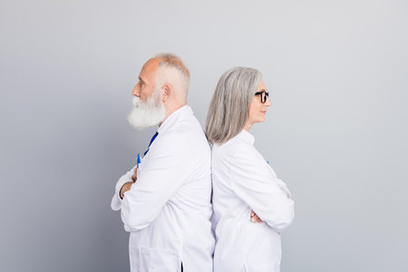 Two experienced doctors back to back in white coats a portrait of professional healthcare team ready for medical consultation and patient careの写真素材