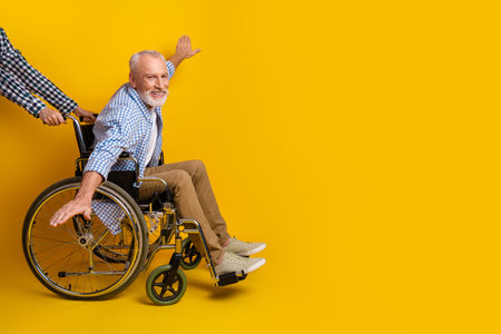 Grandpa in a bright wheelchair scene brings joy mobility and care in a sunny yellow studio backdropの写真素材