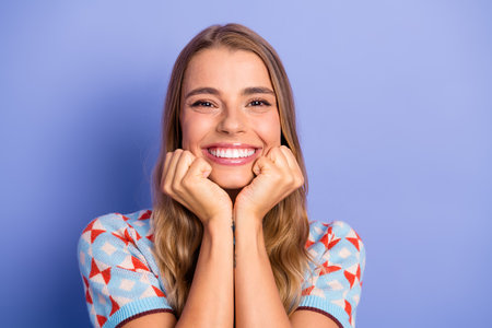 Smiling young woman with blonde hair in a patterned sweater against a blue backgroundの写真素材