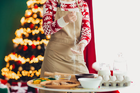 Funny baker in festive sweater sprinkles sugar while Christmas joy fills a cozy kitchen for holiday celebrationの写真素材