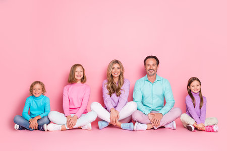 Family gathering with parents and children smiling together in pastel pink studio for love joy and warm togethernessの写真素材
