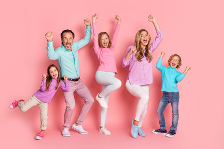 Family joy and togetherness as parents and kids celebrate and jump for happiness against a pink backdropの写真素材