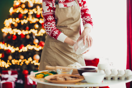Playful baker in a cozy kitchen creates festive treats beside a glowing christmas tree and warm home holiday vibesの写真素材