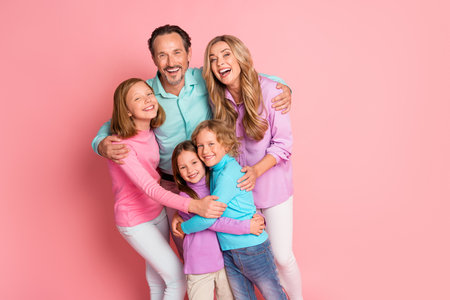 Family together in a joyful pink background with parents and children smiling and embracing a warm scene perfect for love happiness and bonding across celebrationsの写真素材